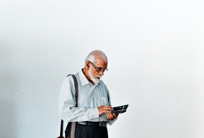 A man in a dress shirt and suspenders holding a tablet