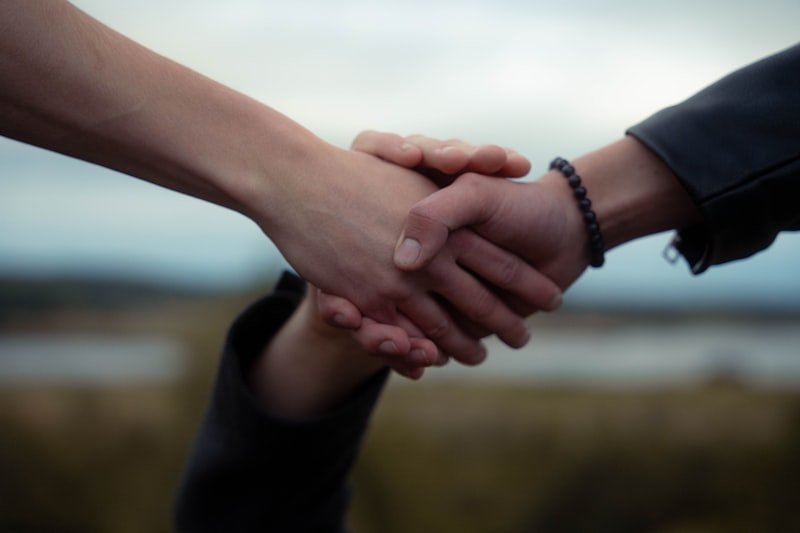 Two people shake hands, possibly a deal.