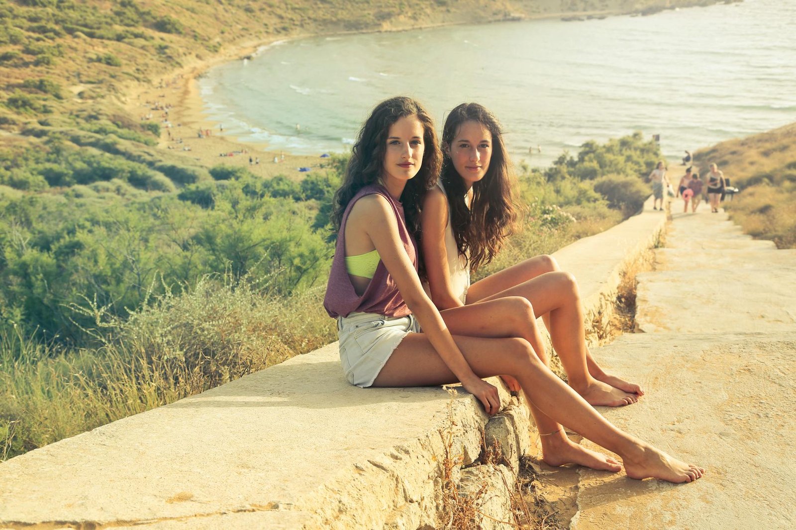 Two women enjoying a sunny day at Mgarr Beach, Malta. Perfect summer relaxation spot.