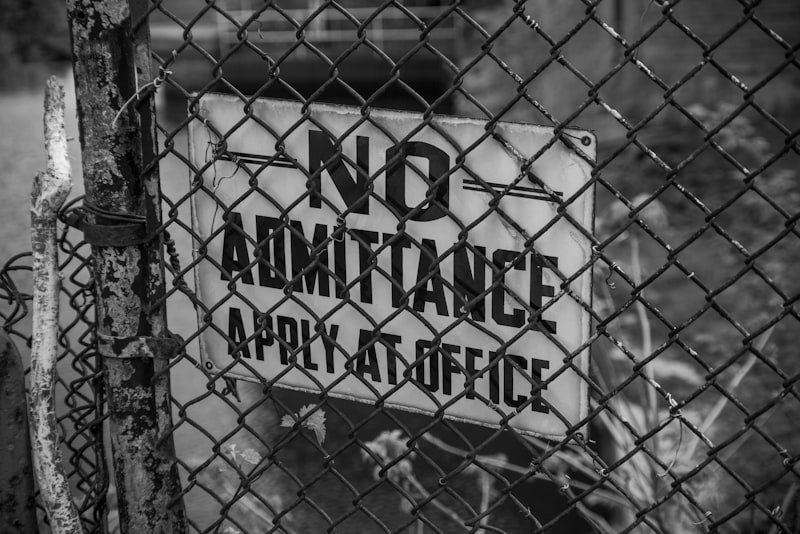 grayscale photo of metal fence with no smoking sign