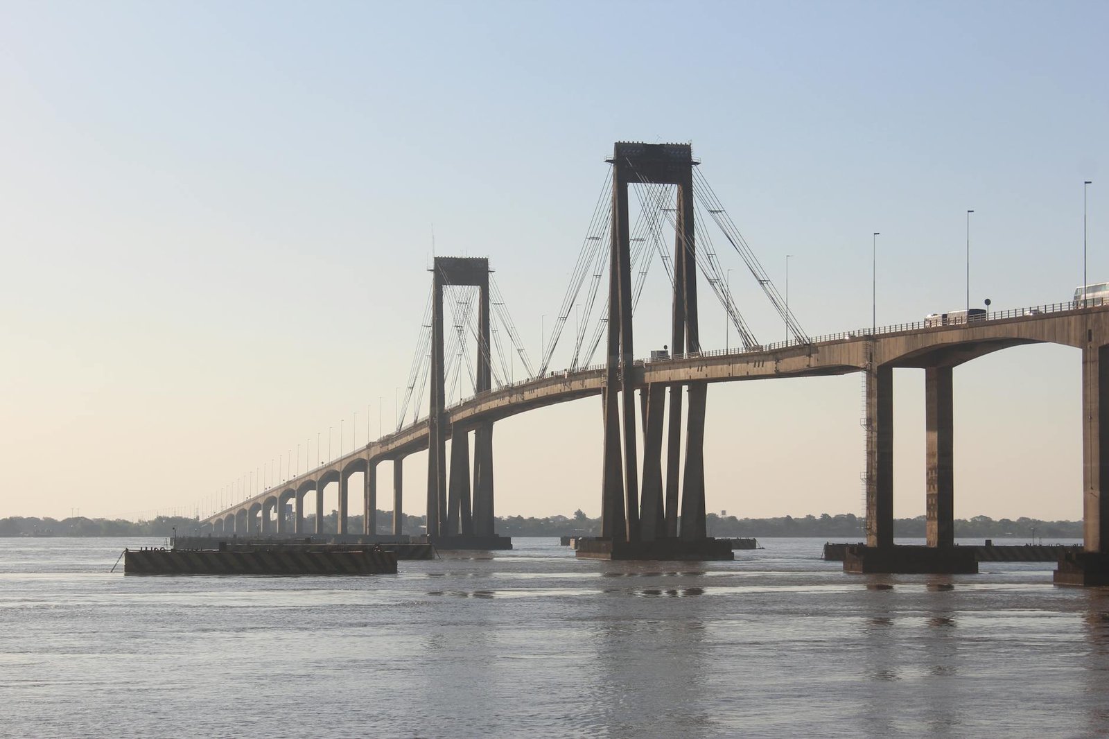 A suspension bridge over a river captured during the serene golden hour, showcasing modern infrastructure.