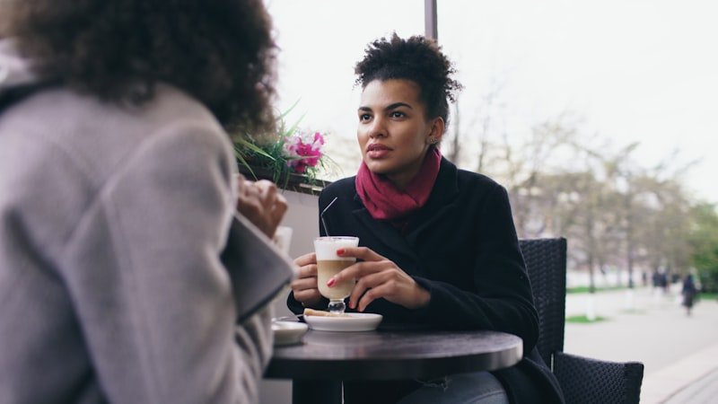 Two women talking at an outdoor cafe table.