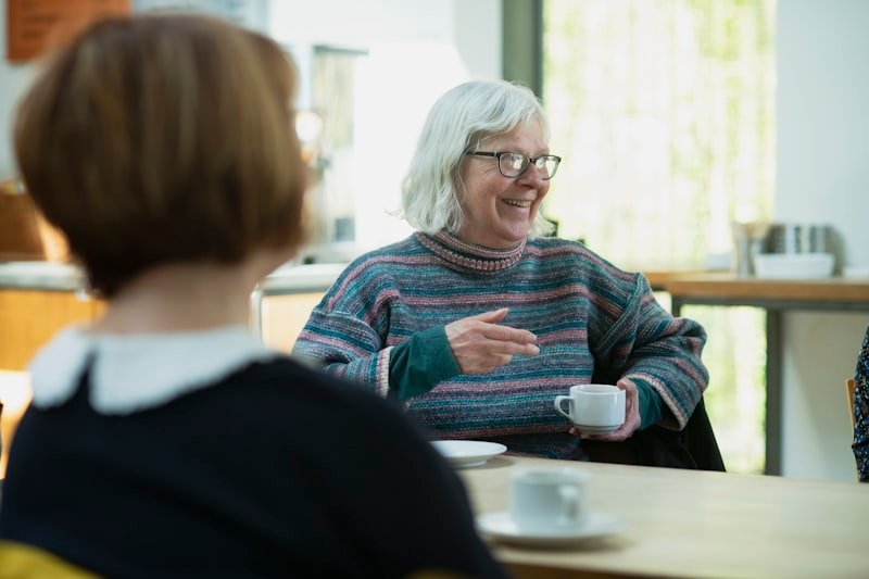 a woman sitting at a table talking to another woman