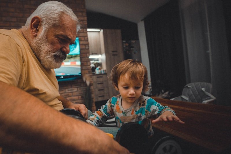 an older man and a young boy playing with a toy car