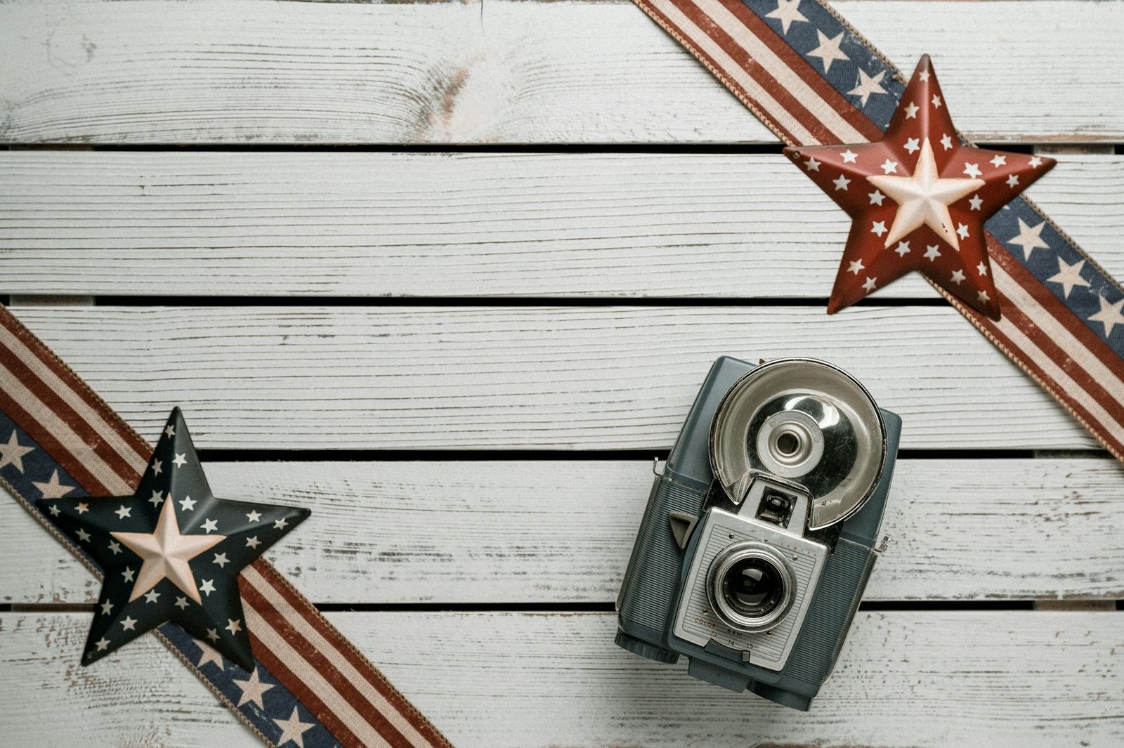 A classic vintage camera on rustic wood with American star decorations, perfect for a vintage Americana theme.