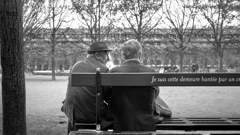 grayscale photo of man and woman sitting on bench