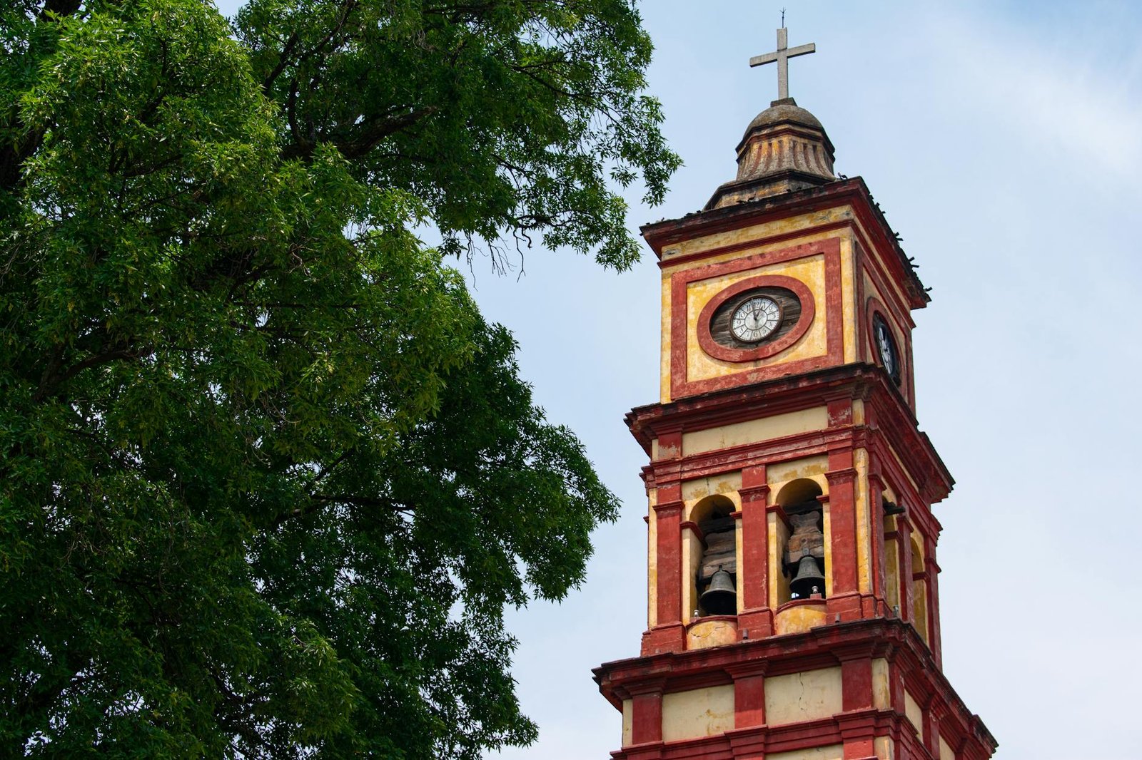Historic bell tower in Lerma de Villada captured during a sunny day with lush greenery.