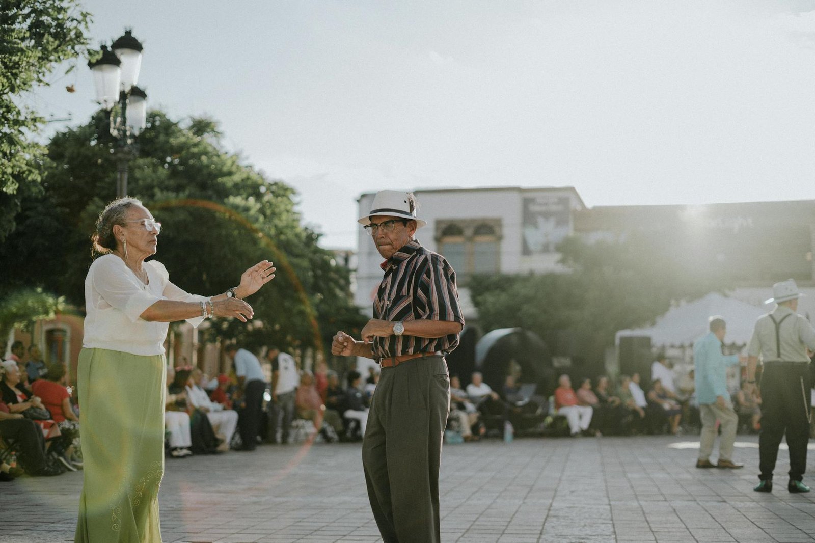 Elderly couple dancing in sunlit León de los Aldama plaza, showcasing joy and community spirit.