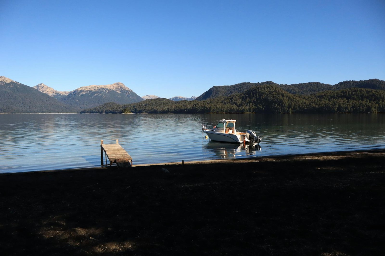 A tranquil boat scene on a lake surrounded by mountains in Villa La Angostura, Argentina.