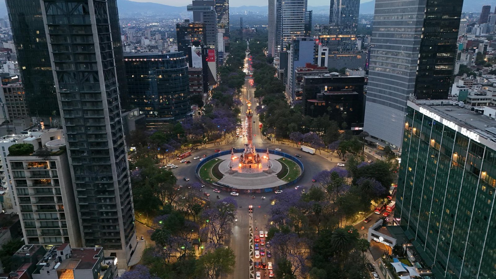 Stunning aerial shot of Paseo de la Reforma in Mexico City with jacaranda trees and city lights.