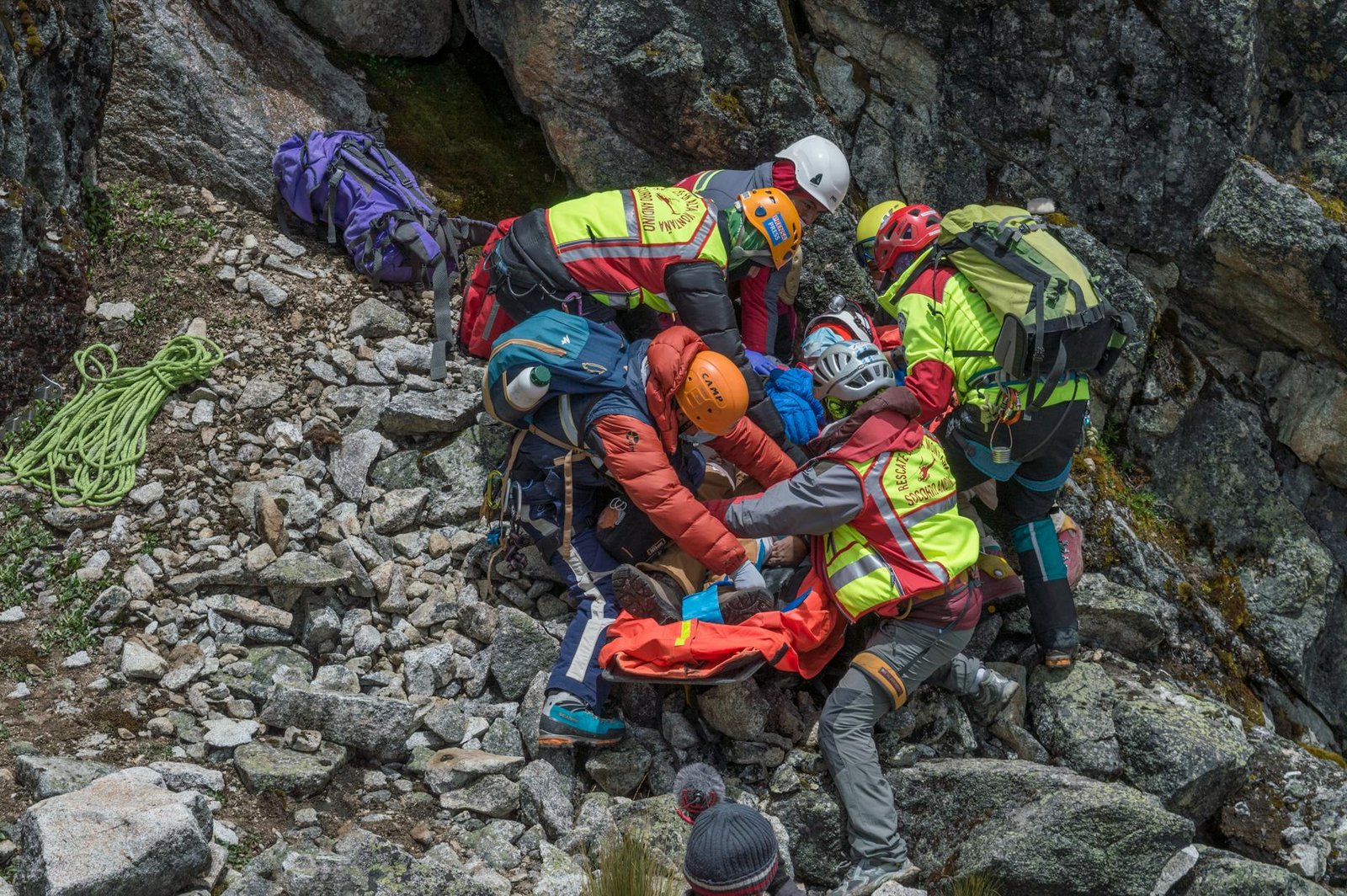 Mountain rescue team assisting injured climber on rocky mountainside in Bolivia.