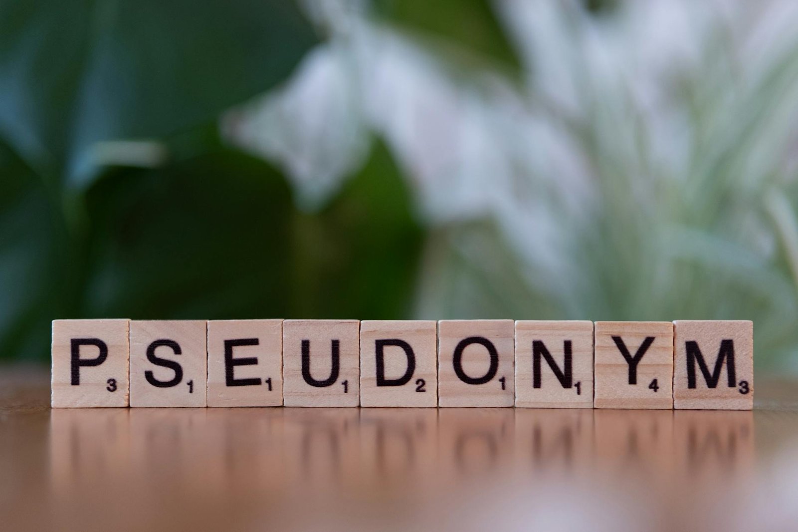 Wooden letter tiles spelling 'Pseudonym' on a table with a blurred background.