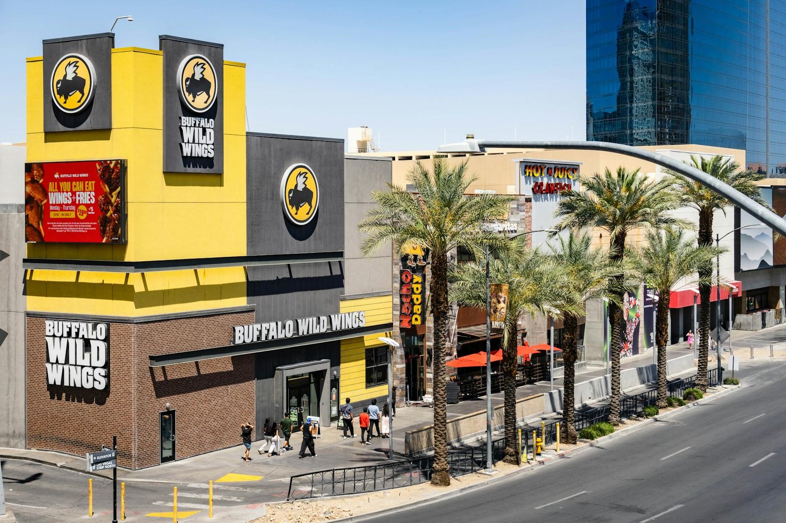 Buffalo Wild Wings located on the bustling Las Vegas Strip with palm trees and pedestrians.