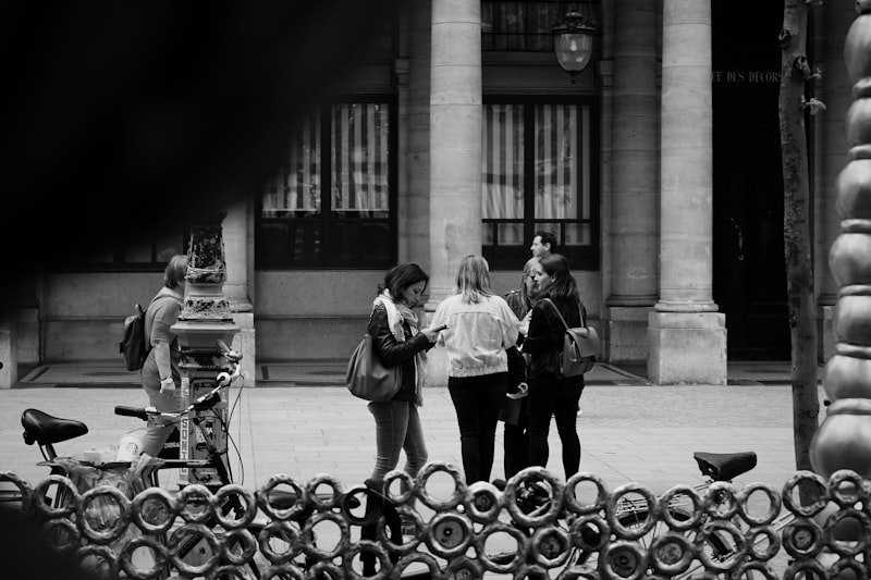 grayscale photo of woman and man standing near building