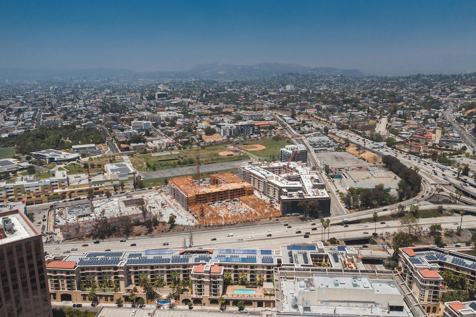 Aerial view showcasing the urban sprawl of Los Angeles with construction sites and highways visible.