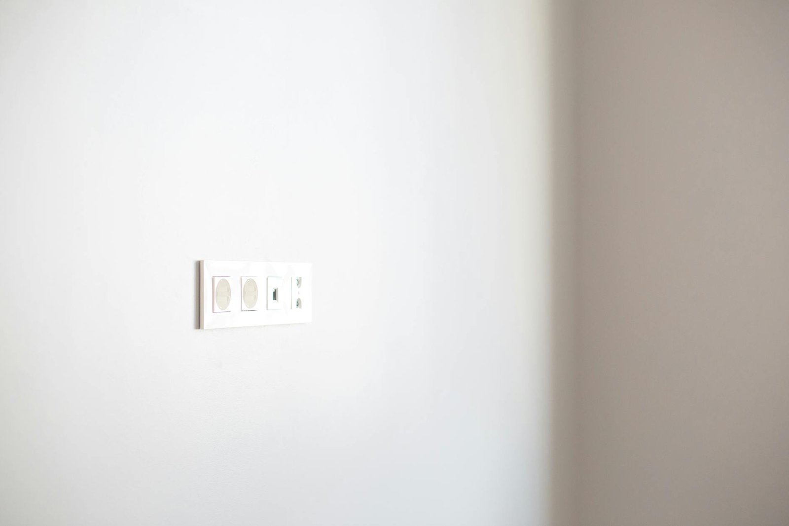 Close-up of a white wall featuring a modern electrical outlet, ideal for design concepts.