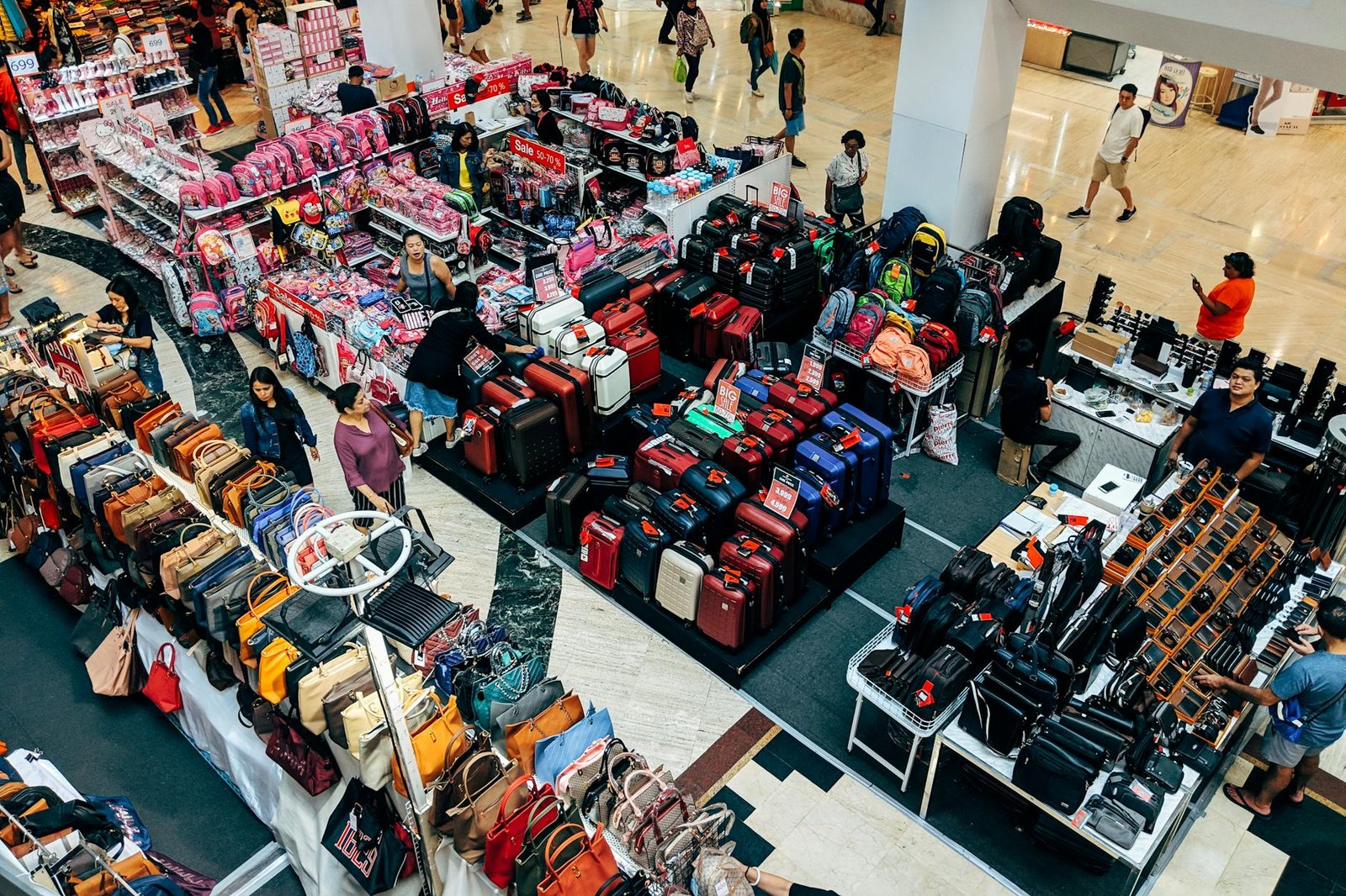 Overhead view of a vibrant shopping area in a Bangkok mall featuring purses, suitcases, and bustling shoppers.