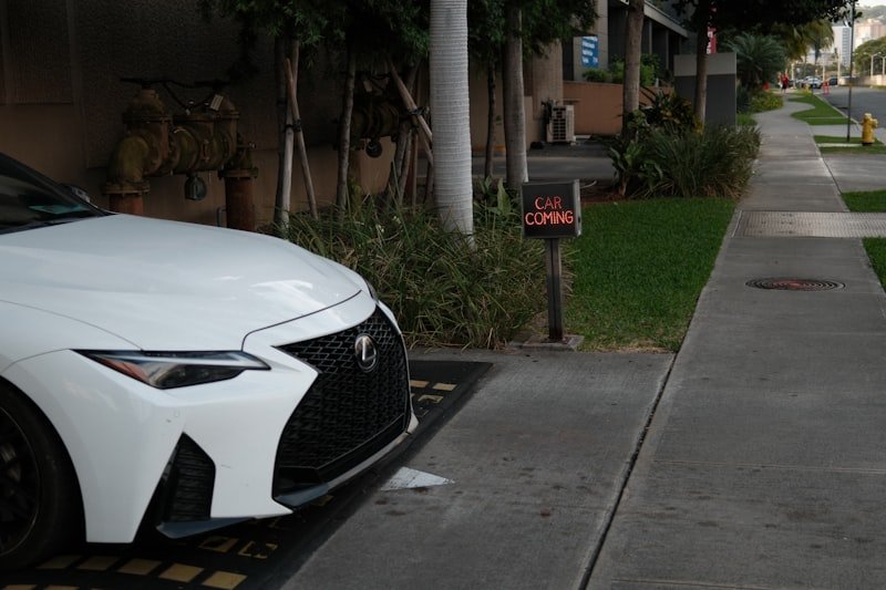White car parked by a sidewalk and mailbox.