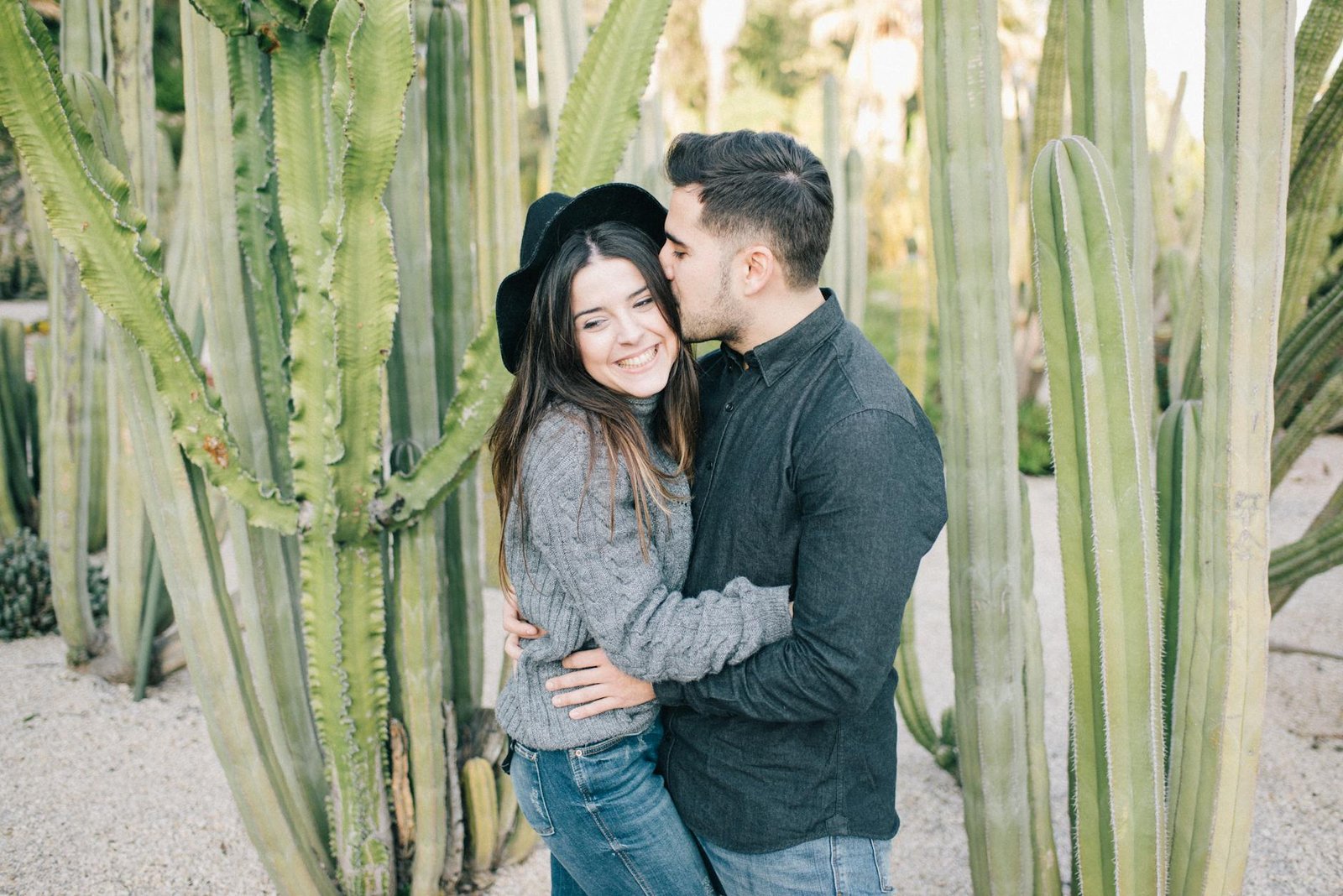 A joyful couple cuddling amidst tall cacti, symbolizing love and nature.