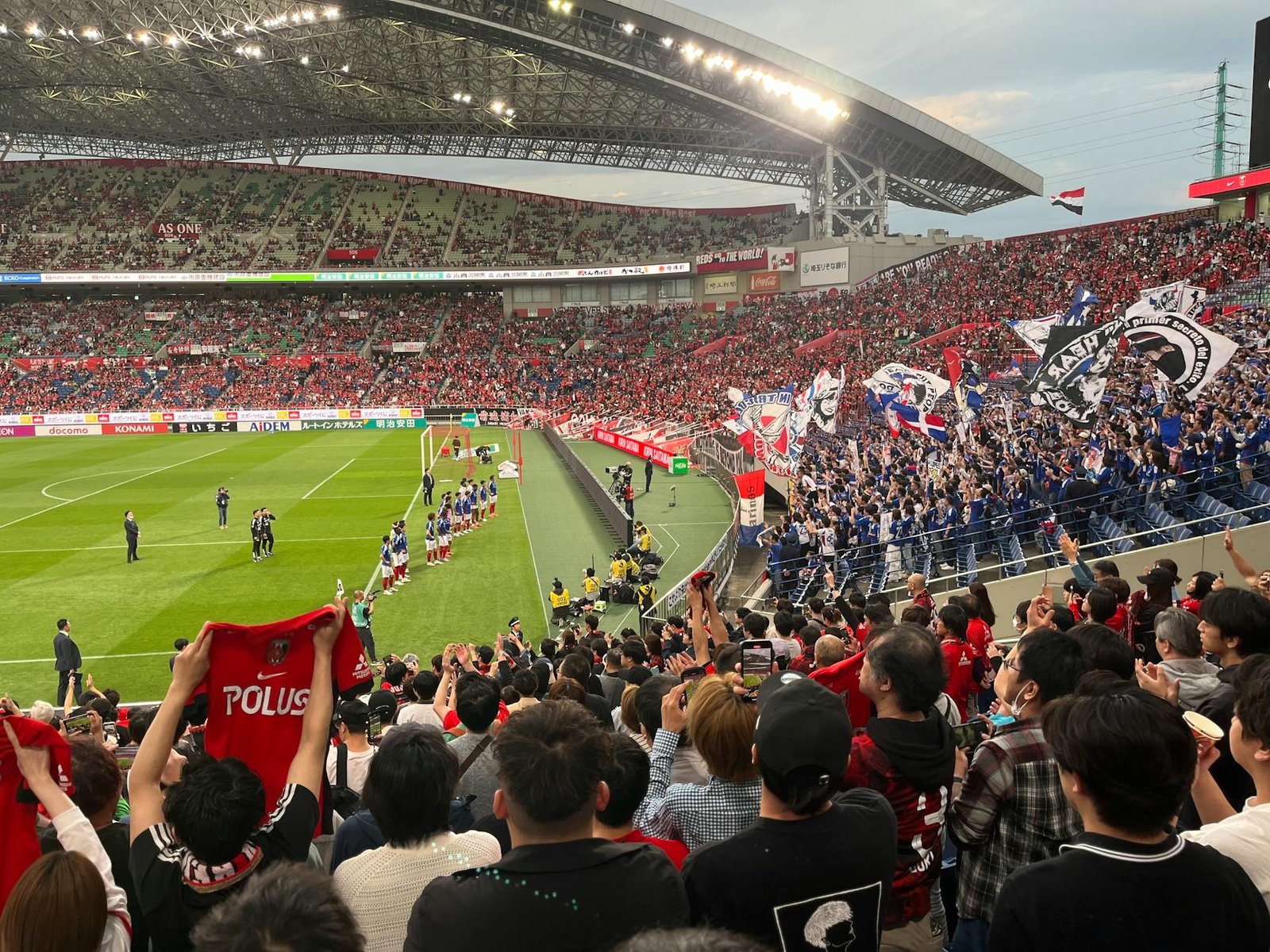 A thrilling soccer match at a packed stadium with energetic fans waving flags and cheering in Japan.
