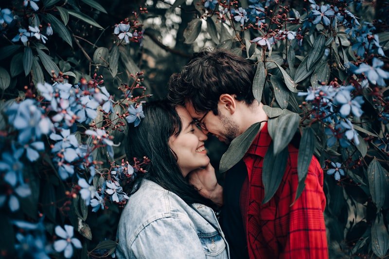 man about to kiss the woman near the white petaled flower