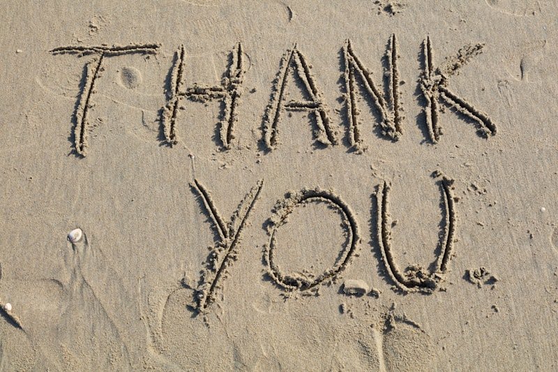Thank you is written on the sand.
