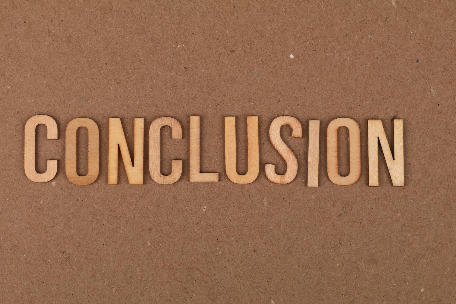 Wooden letters arranged to spell 'Conclusion' on a brown cardboard background.